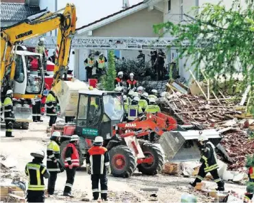  ?? DPA ?? Feuerwehrl­eute und Rettungskr­äfte räumen mit schwerem Gerät die Trümmer beiseite.