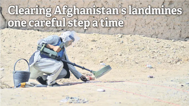  ?? — AFP photos ?? A deminer from the HALO Trust scanning the ground for mines with a metal detector in Nad-e-Ali village in Helmand province.