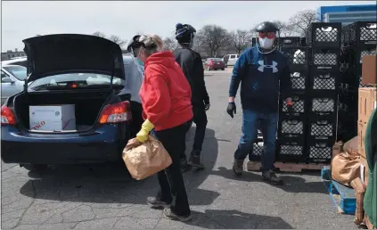  ?? PHOTOS BY GINA JOSEPH — MEDIANEWS GROUP ?? Forgotten Harvest workers load food into a trunk at one of their 17mobile food pantries operated in Oakland, Macomb and Wayne counties.