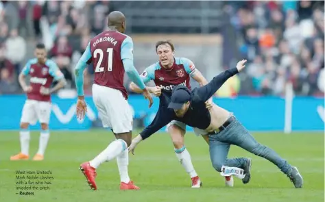  ?? — Reuters ?? West Ham United’s Mark Noble clashes with a fan who has invaded the pitch.