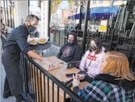  ?? Marcio Jose Sanchez The Associated Press ?? Customers are served lunch Tuesday in Pasadena, Calif. The city has its own public health department and does not have to adhere to rules implemente­d by L.A. County.