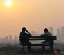  ??  ?? A couple watches the sun set on the Calgary skyline. The smoke in the air had turned the sun into a bright glowing ball.