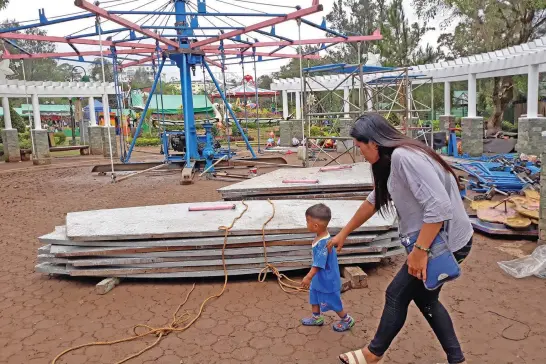  ?? Photo by Milo Brioso ?? SHUTTING DOWN. A mother and child enjoys a stroll at the children’s park amid the carnival which is set to remove rides after the City Council snubbed a plea for extension.