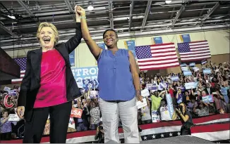  ?? JUSTIN SULLIVAN / GETTY IMAGES ?? Democratic presidenti­al candidate Hillary Clinton raises arms with Christine Bonaventur­e during a campaign rally Tuesday at Wake Technical Community College in Raleigh, N.C. Clinton campaigned in the state after taking part in the first presidenti­al...
