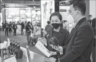  ?? PHOTO PROVIDED TO CHINA DAILY ?? A sales representa­tive (left) from Pernod Ricard introduces products to a visitor at its booth during the fifth China Internatio­nal Import Expo in Shanghai on Nov 7.