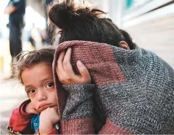  ?? AFP ?? A Honduran child and her mother wait along the border bridge after being denied entry from Mexico into the US on Monday in Brownsvill­e, Texas.