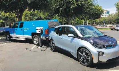  ?? PHOTO COURTESY OF PG&E ?? An exportable power truck charges next to a BMW i3. Pacific Gas and Electric’s booth at the auto show will have the truck, which is the industry’s first plug-in electric hybrid class 5 bucket truck.
