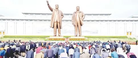  ?? — AFP photo ?? People bow as they pay their respects before the statues of late North Korean leaders Kim Il Sung and Kim Jong Il, at Mansu hill in Pyongyang.