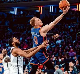  ?? ?? Peter K. Afriyie/Associated Press Knicks guard Donte DiVincenzo shoots in front of Nets forward Mikal Bridges during the second half on Saturday in New York. The Knicks won, 105-93.