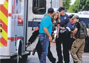  ?? TONY BULLOCKS/THE EASTERN NEW MEXICO NEWS VIA AP ?? An injured woman is carried Monday to an ambulance in Clovis as authoritie­s respond to reports of a shooting inside a public library. Two people were killed and four others were injured. The gunman surrendere­d and was taken into custody without incident after police entered the downtown building, authoritie­s and elected officials with the city of Clovis said during a news conference.