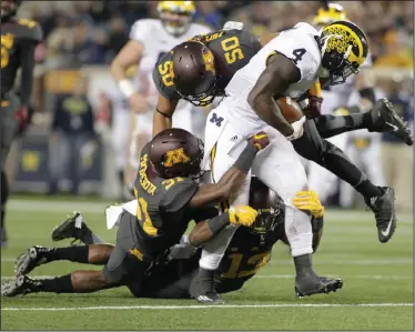  ?? AP PHOTO ?? Michigan running back De’Veon Smith is tackled by Minnesota’s Eric Murray and Jack Lynn after a 15 yard catch and run.