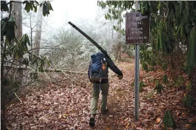  ?? STAFF PHOTOS BY DOUG STRICKLAND ?? Mason Boring, with Southern Appalachia­n Wilderness Stewards, carries a two-man saw to clear downed trees on the Fodderstac­k Trail of the Citico Creek Wilderness in the Cherokee National Forest on Thursday in Monroe County, Tenn.