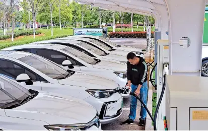  ??  ?? The man is charging a new energy vehicle in Jiangxi Province. — IC