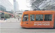  ?? Ted S. Warren, The Associated Press ?? A streetcar with an advertisem­ent for Amazon.com’s same-day delivery passes by an Amazon office site Tuesday in Seattle’s South Lake Union neighborho­od. Average city rents in Seattle have increased to nearly $2,000 per month.