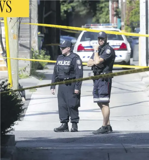 ?? CRAIG ROBERTSON / POSTMEDIA NEWS ?? Police officers stand guard in laneway north of Toronto’s Danforth Avenue after a mass shooting on July 23.