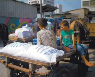  ?? MOHAMMED ABED AGENCE FRANCE-PRESSE ?? Des enfants palestinie­ns sont assis sur un chariot transporta­nt des vivres fournis par l’UNRWA.