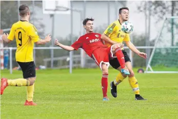  ?? FOTO: THOMAS WARNACK ?? Zweikampf zwischen Hohentenge­ns Kai Remensperg­er (rotes Trikot, M.) und Bad Buchaus Fabian Baur (rechts). Mathias Fischer beobachtet die Szene, kann aber nicht mehr eingreifen.