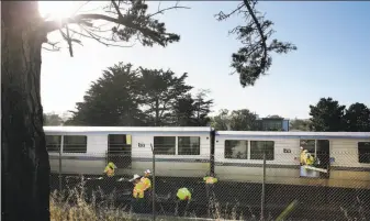  ?? Santiago Mejia / The Chronicle ?? Workers examine derailed BART cars in Daly City. The wheels on the two middle cars of a nine-car train came off the tracks on the way to Balboa Park Station, forcing evacuation­s.