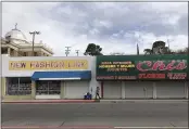  ?? SUMAN NAISHADHAM — THE ASSOCIATED PRESS ?? A woman walks past two out-of-business clothing stores located steps away from the U.S.-Mexico border in Nogales, Ariz.