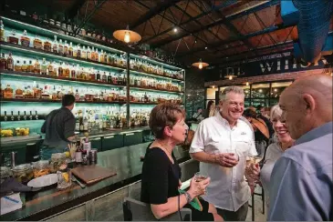  ?? JASON GETZ/FILE PHOTO ?? Malcolm O’Hara, center, and his wife, Cindy, left, enjoy a cocktail with their neighbors Bob Moore and his wife, Linda Cabot, at The Whiskey Project last year in Roswell.