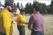  ?? GEOFFREY PLANT/Taos News ?? Lt. Gov. Howie Morales greets Angelo LeDoux, center, and LeDoux’s fellow wild land firefighte­rs with the Angel Fire Fire Department, Justin Williams and Micah Talbot, who deployed hose lines, pumps and sprinklers to protect structures south of Angel Fire.