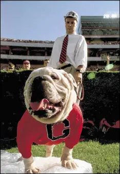  ?? AJC 1999 ?? Uga V chills atop a bag of ice — a cool tradition for the mascot during games — in front of handler Charles Seiler at his last football game at Sanford Stadium. There’s only one Uga, but about 40 other U.S. colleges and universiti­es also have bulldog mascots.