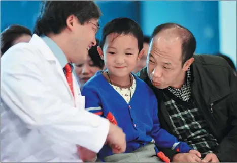  ?? CHEN JIMIN / CHINA NEWS SERVICE ?? Dennis Lam Shun-chiu (left), an eye doctor from Hong Kong, sends his best wishes to 6-year-old Guo Bin on Thursday, as he left Lam’s hospital in Shenzhen after surgery to implant cosmetic eyes. The boys’ eyes were gouged out by his aunt in August.