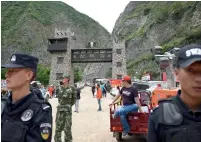  ?? AFP ?? Police stand their guard at an entrance of a road to a landslide area in the village of Xinmo in Maoxian county. —