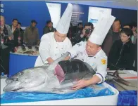  ?? XU HEDE/FOR CHINA DAILY ?? Two employees from Shanghai Fisheries Group Co Ltd serve tuna at an industry expo held in Shanghai.