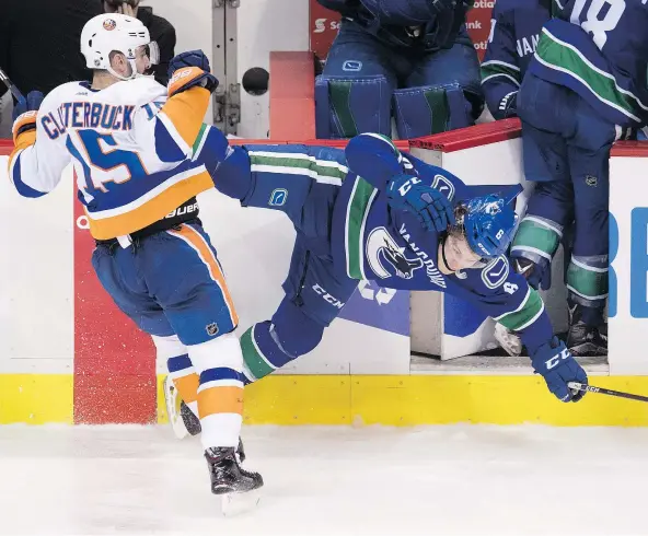  ?? — THE CANADIAN PRESS ?? New York Islanders’ Cal Clutterbuc­k, left, checks Vancouver’s Brock Boeser into the open player’s bench door during a game in March. The hit left Boeser with a back fracture and knocked him out of the running for the NHL’s rookie of the year.