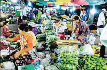  ?? SAHIBA CHAWDHARY ?? Vendors prepare stalls to sell fresh vegetables and fruits at a Phnom Penh market.