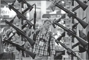  ?? JULIE JACOBSON/AP FILE PHOTO ?? Michael Kiefer of DeFuniak Springs, Fla., checks out a display of rifles at the Rock River Arms booth in January 2013, during the 35th annual SHOT Show in Las Vegas, Nev. The largest gun industry trade show is taking place in Las Vegas, just a few...