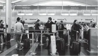  ?? Stefani Reynolds / Washington Post correspond­ent ?? Travelers wait in line Sunday at an American Airlines kiosk at Reagan National Airport. Parking spots nationwide are growing scarce as passengers choose to drive themselves to airports.