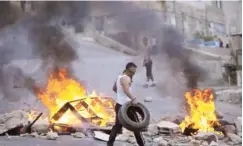  ??  ?? Palestinia­ns burn tires during Israeli military raid in the West Bank city of Nablus, yesterday.