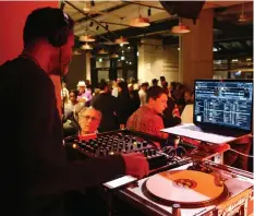  ?? JEAN LEVAC ?? A DJ keeps the sounds coming, as guests mill about, at the invitation-only launch party of the Queen St. Fare food hall on Thursday.