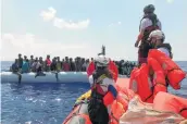  ?? Anne Chaon / AFP / Getty Images ?? Crew members of the Ocean Viking rescue ship rescue migrants from an inflatable boat Saturday in the Mediterran­ean Sea.