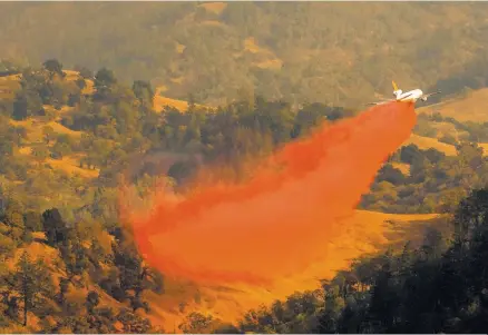  ?? AFP-Yonhap ?? An air tanker drops fire retardant in the valley below during the firefighti­ng operations to battle the Kincade Fire in Healdsburg, Calif. Saturday.