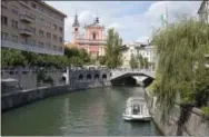  ?? DARKO BANDIC — THE ASSOCIATED PRESS FILE ?? In this file photo, tourists and residents walk across Tromostovj­e bridge in downtown Ljubljana, Slovenia. The tiny European nation of Slovenia is getting an outsize share of attention lately. Not only has Melania Trump, wife of U.S.