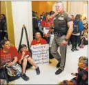  ?? Nate Billings ?? The Oklahoman A state trooper walks by teachers and their supporters Tuesday as they sit in front of the entrance to the House of Representa­tives at the Oklahoma state Capitol in Oklahoma City.