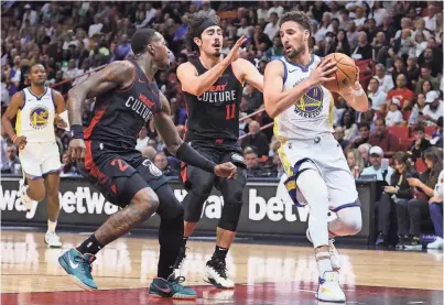  ?? SAM NAVARRO/USA TODAY SPORTS ?? Golden State Warriors guard Klay Thompson, right, drives to the basket past Heat guards Terry Rozier (2) and Jaime Jaquez Jr. on Tuesday in Miami.