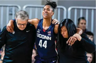  ?? Chris Machian/Associated Press ?? UConn coach Geno Auriemma, left, and UConn athletic trainer Janelle Francisco help Aubrey Griffin off the court Wednesday in Omaha.