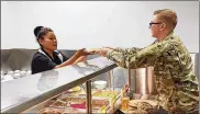  ??  ?? June Martin hands Airman 1st Class Anthony Streichert his lunch of grilled chicken and vegetables on June 17 at Pitsenbarg­er Dining Hall. Color-coded cards help Airmen make healthier selections.