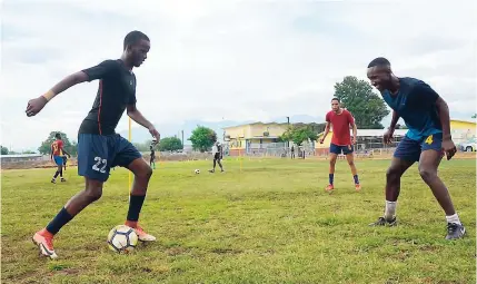  ?? SHORN HECTOR ?? Steven McQueen (left) looks to work his way past Tyrese Smith during a recent St Andrew Technical Manning Cup training session at the school. Watching the play is Tajay Watson (second right).