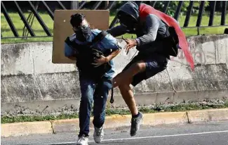  ?? Carlos Garcia Rawlings - 22.jun.2017/Reuters ?? Jovem socorre David José Vallenilla, baleado por militar em protesto na quinta (22)