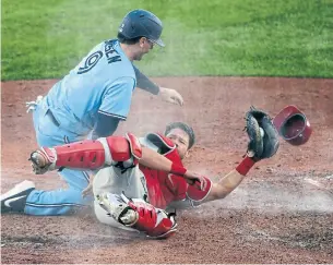  ?? JEFFREY T. BARNES THE ASSOCIATED PRESS ?? Blue Jay Danny Jansen collides with Philadelph­ia Phillies catcher Andrew Knapp and scores on a wild pitch during the second game of Thursday’s doublehead­er in Buffalo.