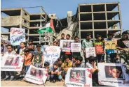  ?? Mahmud Hams / AFP / Getty Images ?? Palestinia­n youths rally outside a building in Gaza City that was struck by an Israeli air raid.