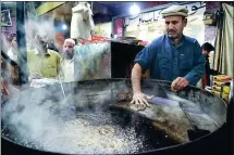  ?? ABDUL MAJEED / AFP ?? A Pakistani cook fries kebabs as customers gather around at the Tory Kebab House in Namak Mandi in Peshawar.