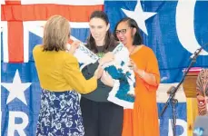  ??  ?? RIGHT: Sonya Rimene, chairwoman of Rangita¯ ne Tu Mai Ra Trust, placing a white korowai decorated with blue feathers as a symbol of
Pu¯ kaha being gifted to the people of New Zealand on Prime Minister Jacinda Ardern.