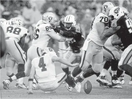  ?? MARK ZALESKI/ASSOCIATED PRESS ?? Quarterbac­k Derek Carr (4) fumbles a snap during a rainy second half of the Raiders’ victory against the Tennessee Titans on Sunday.