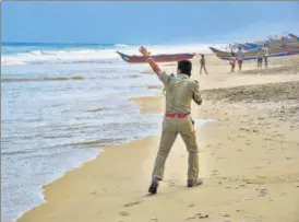  ?? PTI ?? A policeman warns people to steer clear of the coast in Puri, Odisha.